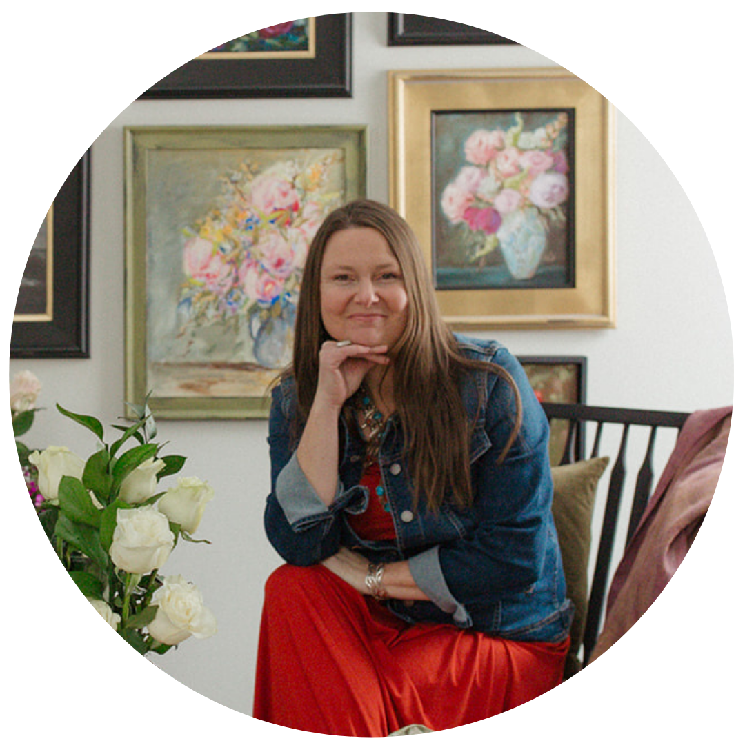 Melissa of the Robin Nest, brunette woman wearing red dress and denim jacket smiling with head resting on her hand